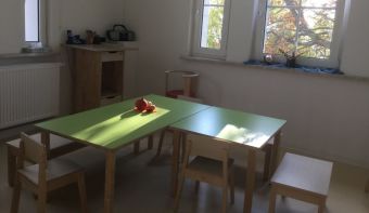 Zu sehen sind zwei aneinander gestellte Tische für Kinder. Sie haben grüne Oberflächen und stehen als L.